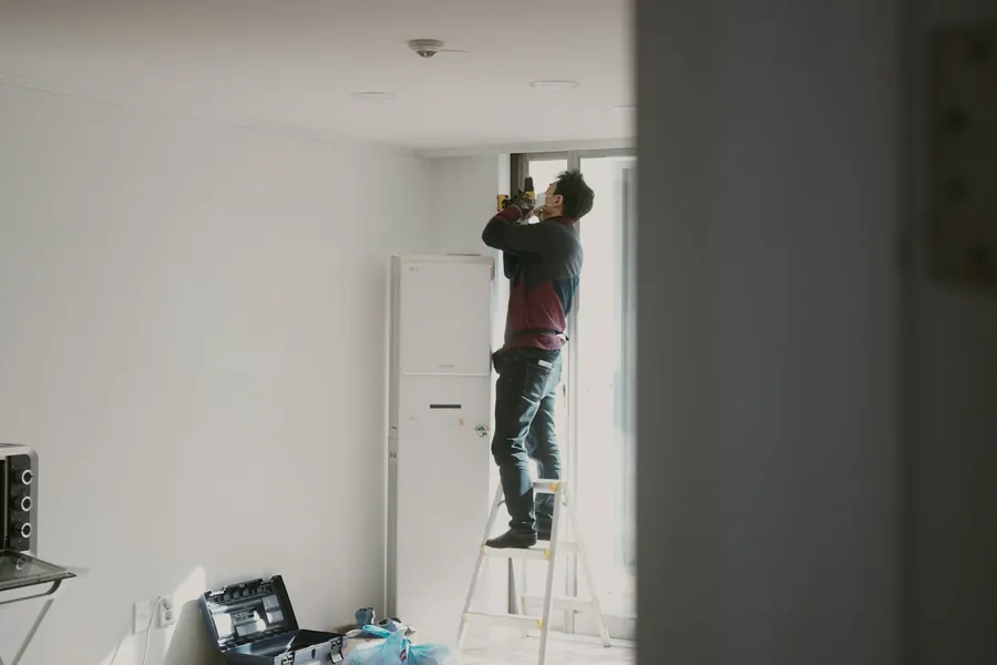 Homme sur une échelle qui travaille au plafond d'un appartement en rénovation