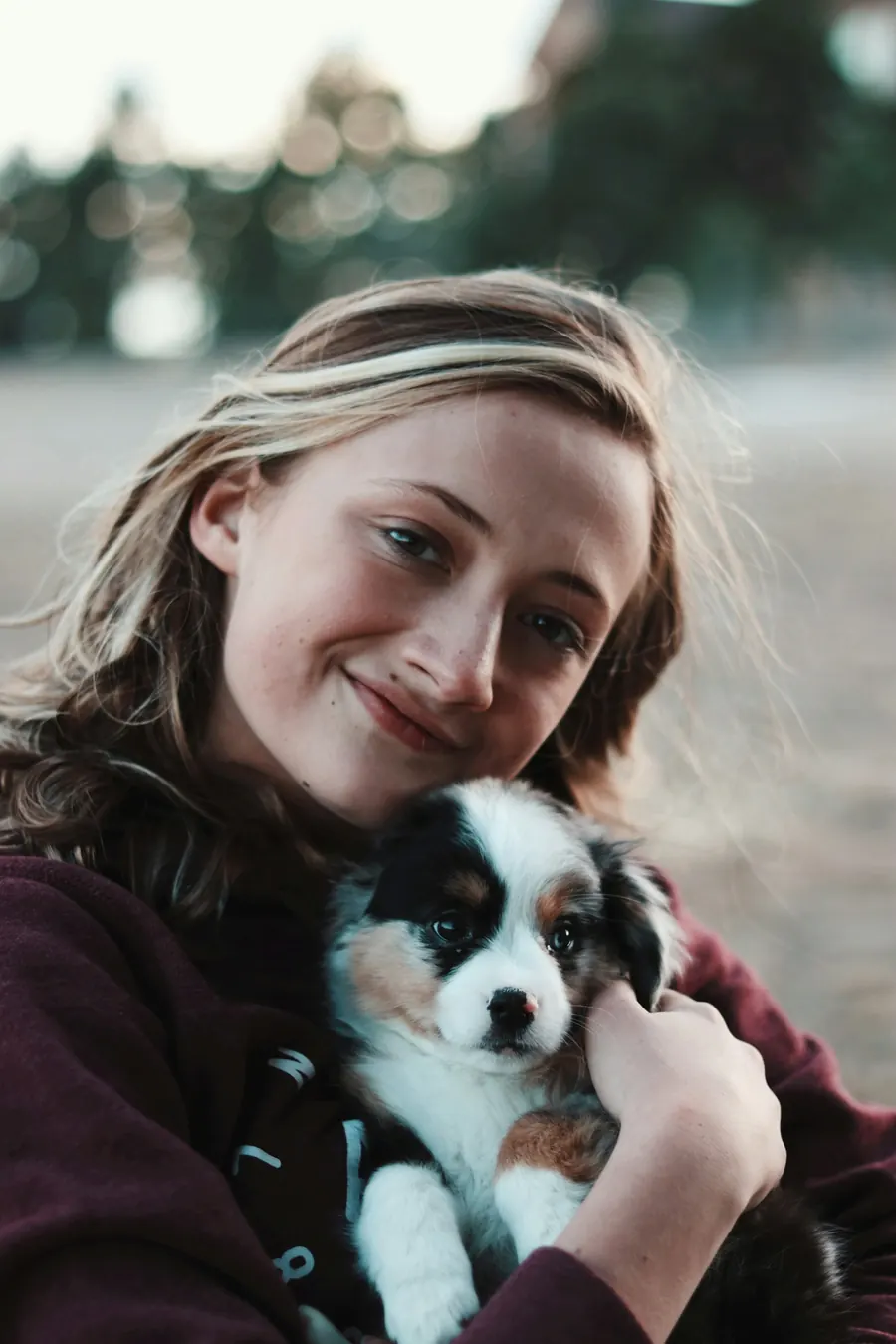 Jeune femme aux yeux bleus qui serre un chiot contre sa joue