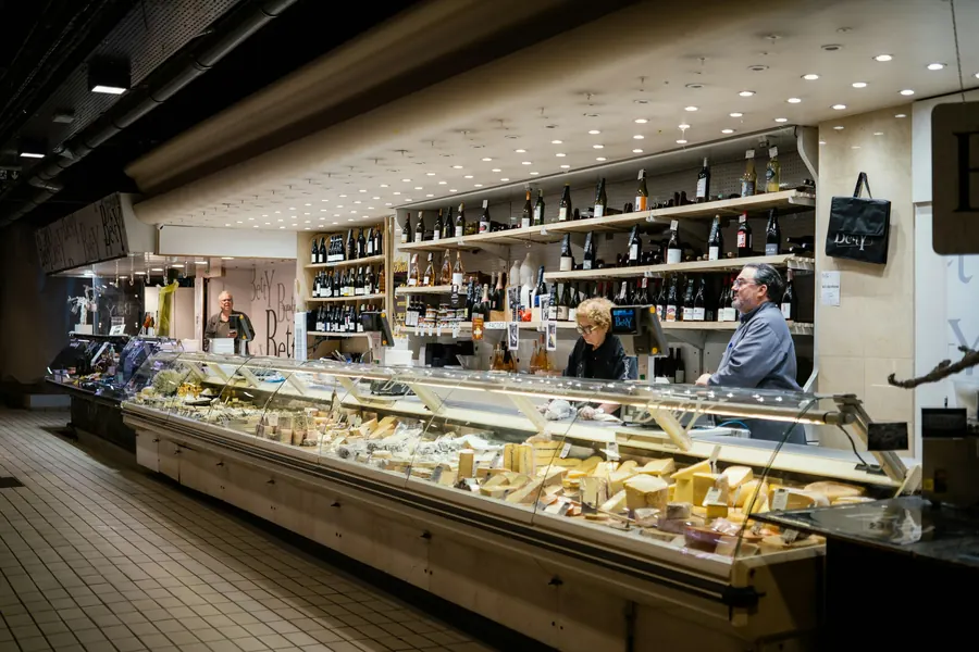 Comptoir d'épicerie fine : meules de fromage, bocaux, étagères en bois, lumière chaude