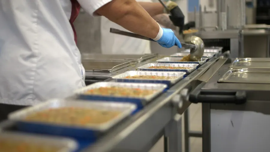 Équipe en tenue de cuisine qui prépare des plateaux-repas dans une cuisine professionnelle