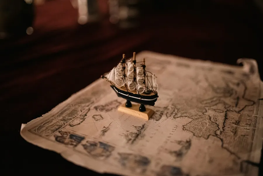 Maquette de bateau posée sur une carte marine ancienne