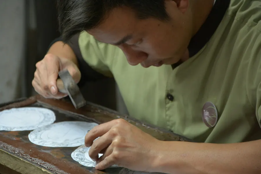 Artisan qui peint une assiette en céramique à la main