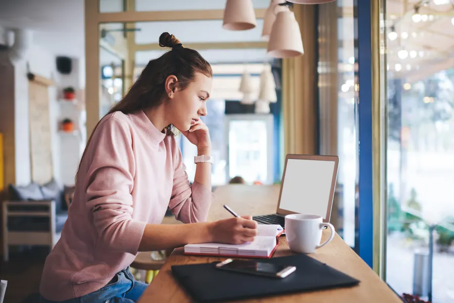 Créatrice d'entreprise de trente ans, ordinateur et carnet, table de café lumineuse