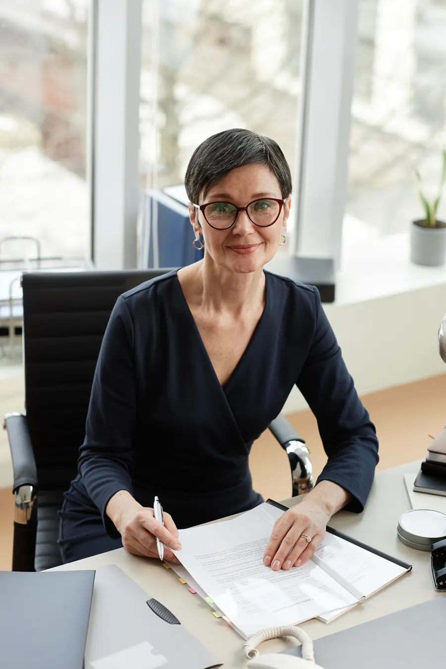 Portrait d'une experte-comptable d'une quarantaine d'années, bureau clair, sourire discret