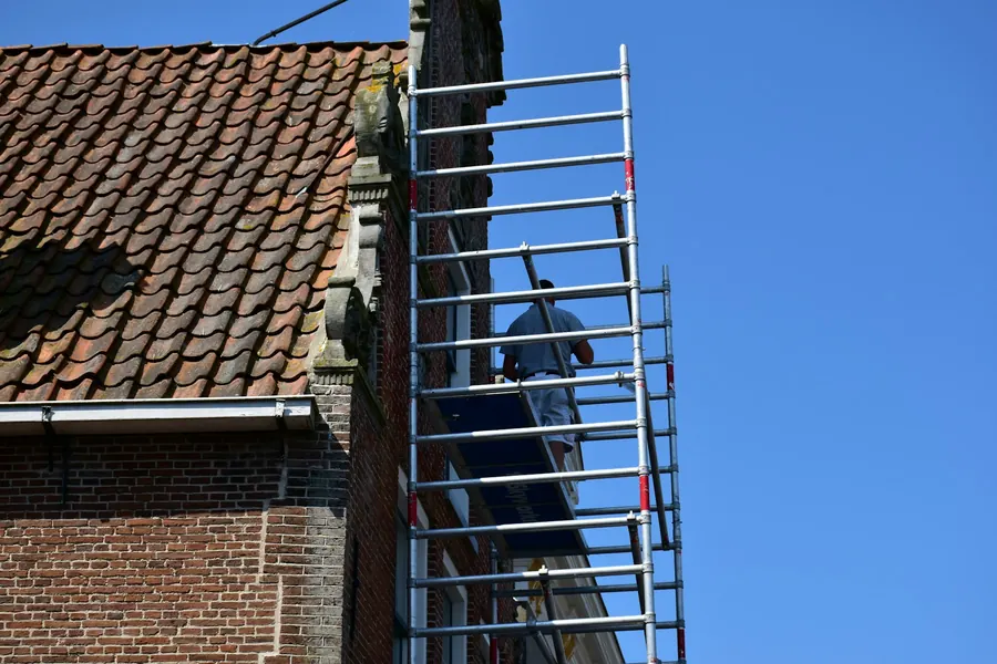 Ouvrier sur un échafaudage contre le toit d'une maison