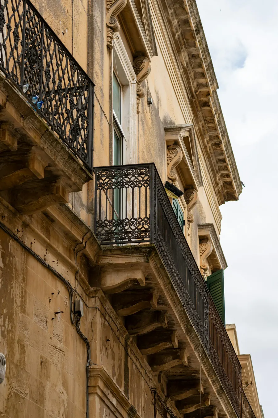 Grille de balcon ancienne en fer forgé sur une façade en pierre