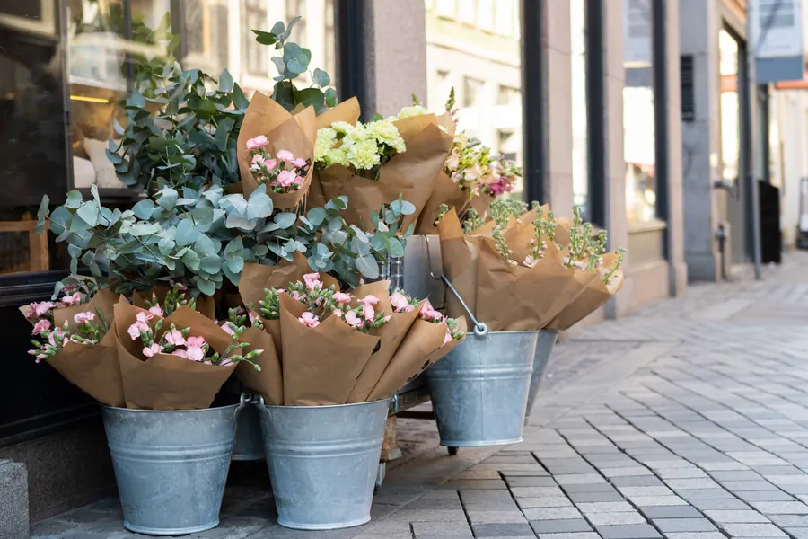 Devanture de fleuriste, seaux de fleurs sur le trottoir, lumière du matin