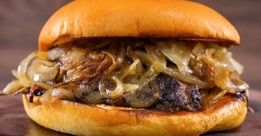 Burger au cheddar et oignons confits, pain brioché, papier kraft, gros plan