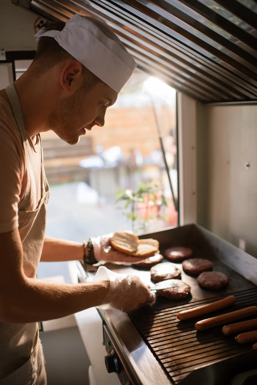 Cuisinier qui saisit des steaks sur la plancha dans la cuisine du camion