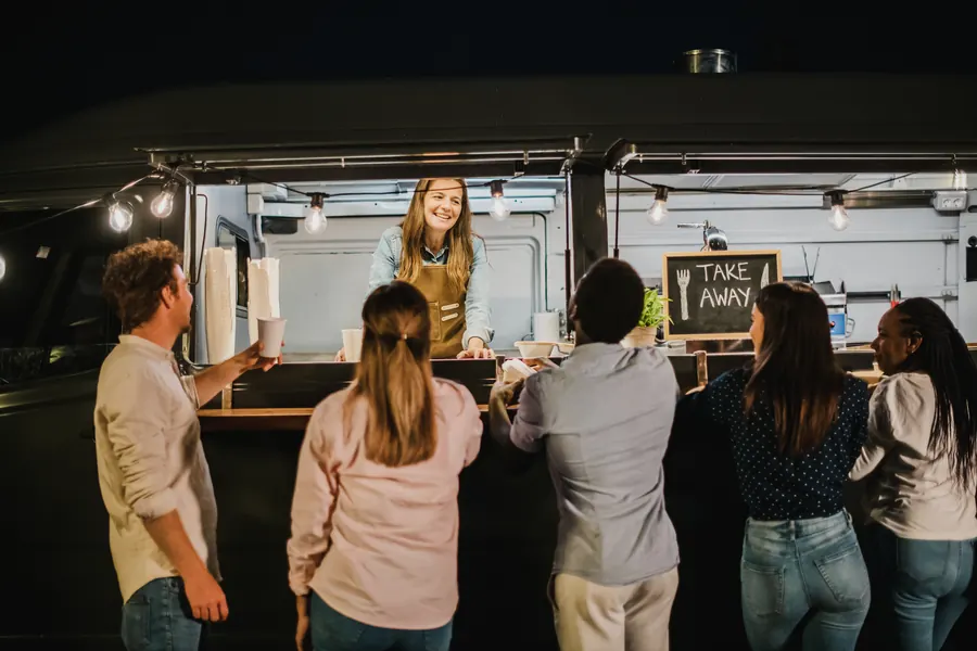 Food truck garé dans un jardin de mariage, guirlandes lumineuses, invités qui font la queue