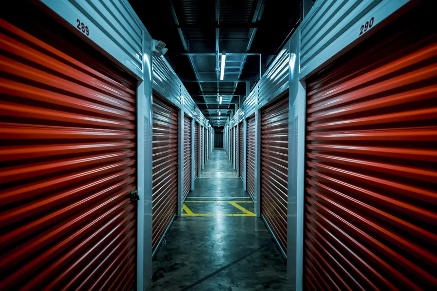 Couloir de box de stockage aux portes rouges en perspective, éclairage froid