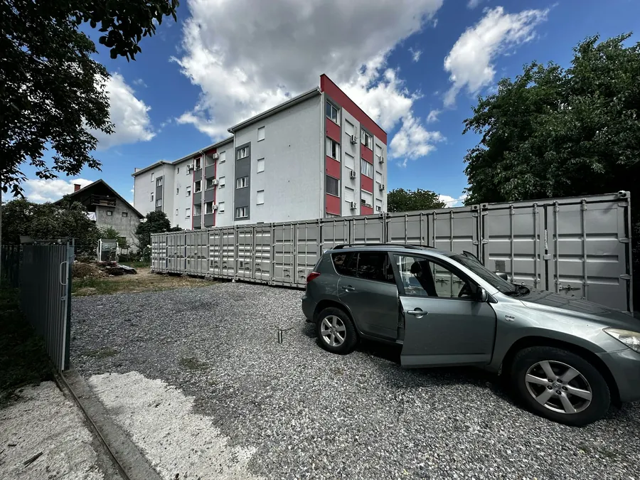 Conteneurs de stockage avec une voiture garée sur un terrain gravillonné
