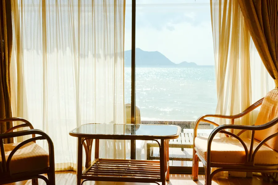 Bureau clair avec deux fauteuils, grande fenêtre ouverte sur la mer, lumière du matin