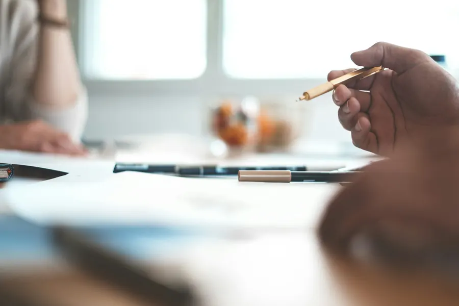 Mains prenant des notes au stylo plume sur un carnet, tasse de café, table en bois