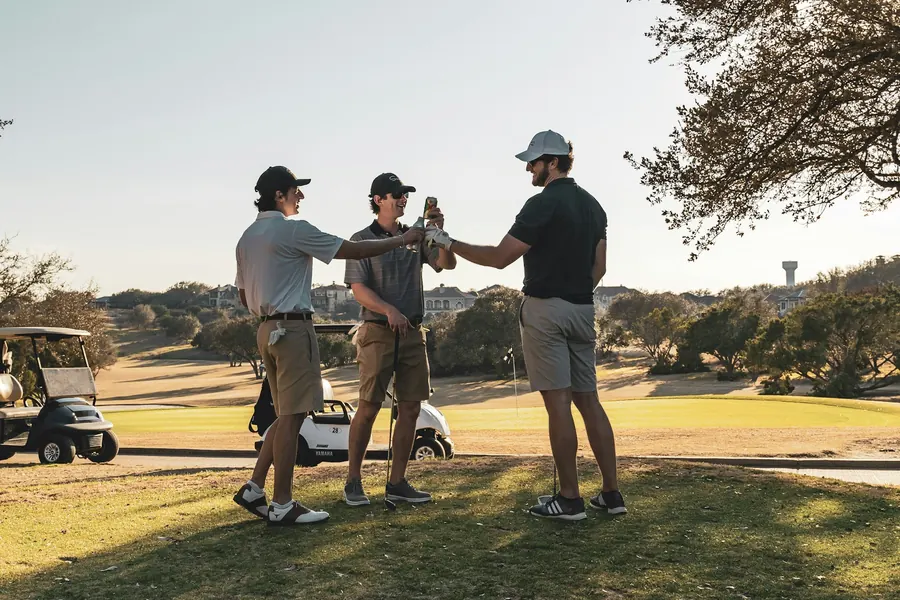 Trois golfeurs se tapent dans la main sur un chemin de golf
