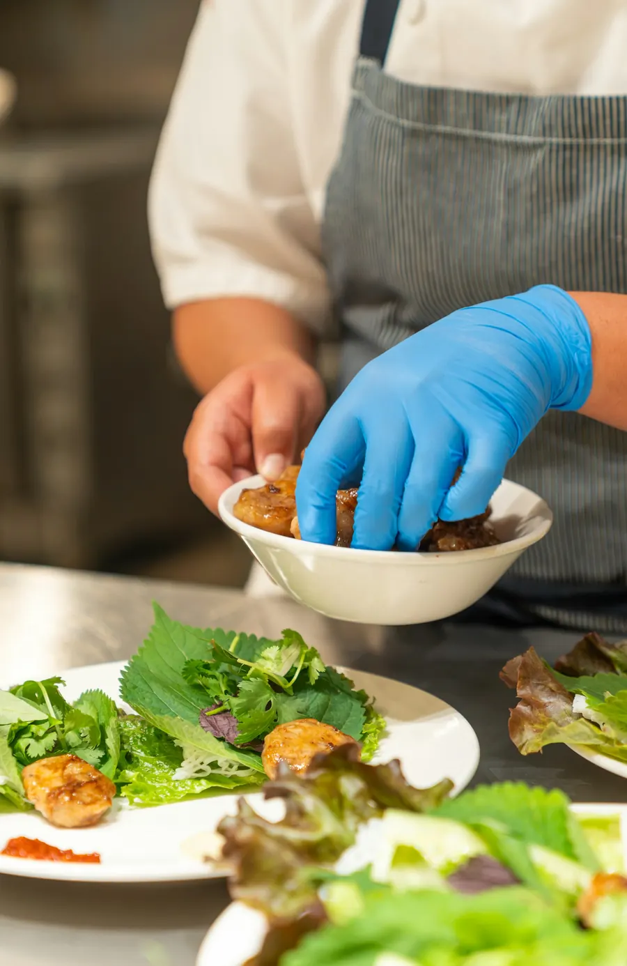 Chef avec des gants bleus qui dresse une assiette