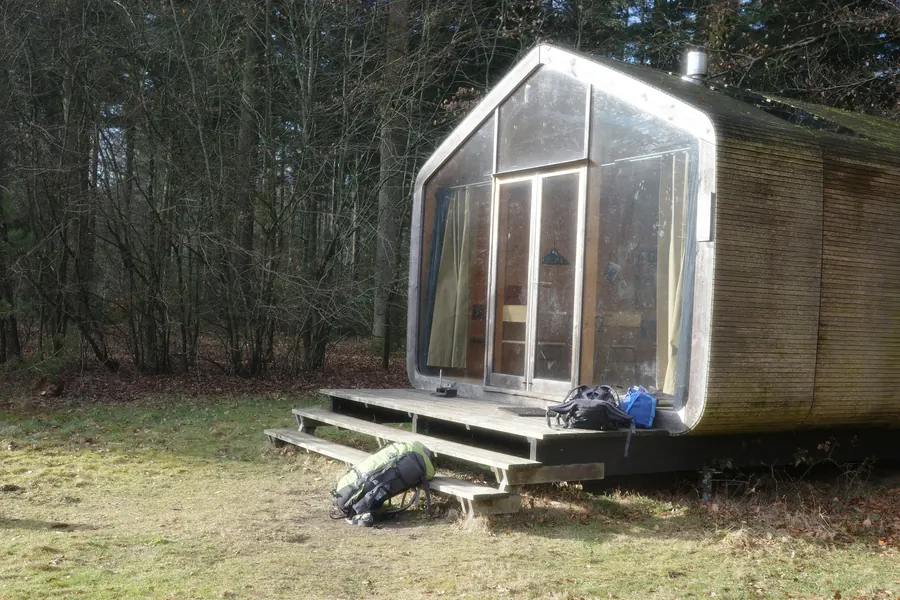 Cabane moderne à baie vitrée dans une clairière, accès par quelques marches