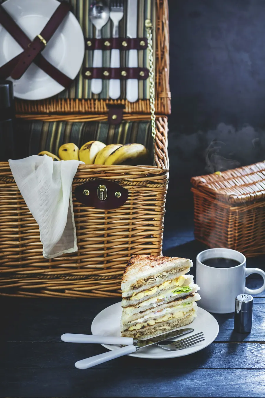 Panier en osier garni de pain et de fruits, tasse de café à côté
