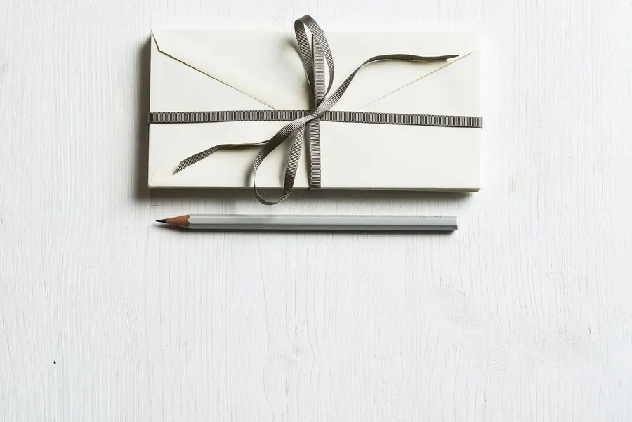 Enveloppe blanche fermée par un ruban, posée sur du papier