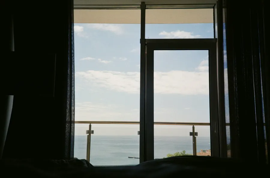 Vue depuis la fenêtre d'une chambre : plage, digue et mer, à hauteur d'œil