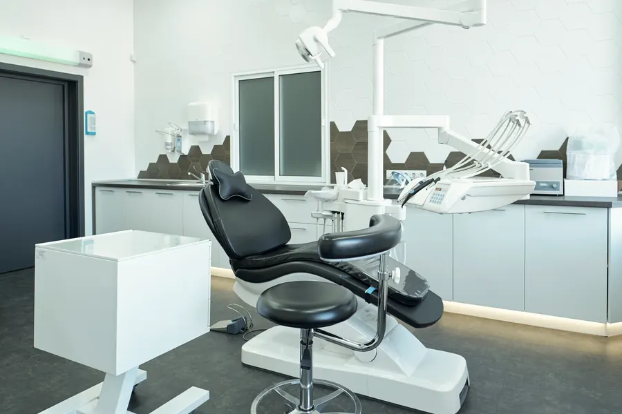 Salle de chirurgie dentaire vide, lampe opératoire, fauteuil et plan de travail nets, en noir et blanc