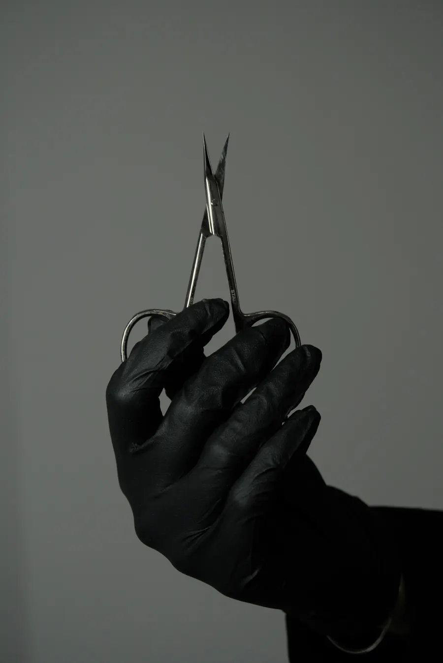 Mains gantées d'un praticien tenant un instrument, fond sombre, en noir et blanc