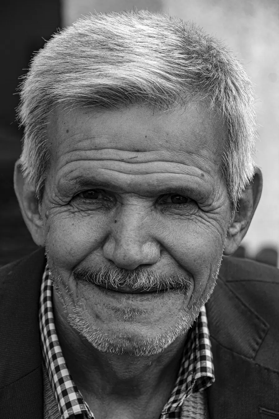 Portrait d'un chirurgien-dentiste d'une cinquantaine d'années, cheveux gris, tenue sombre, regard calme, en noir et blanc