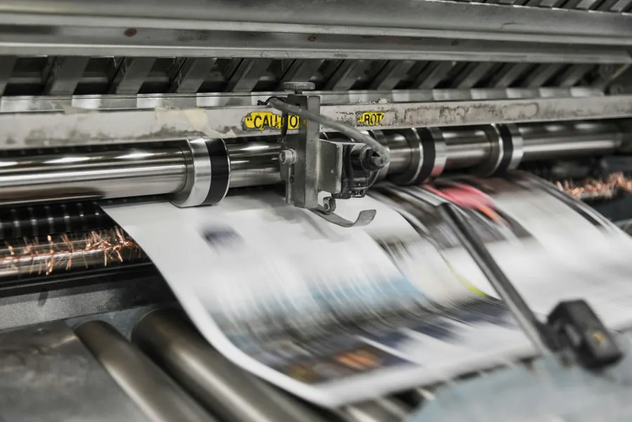 Presse d'imprimerie en marche, feuilles imprimées qui défilent en gros plan