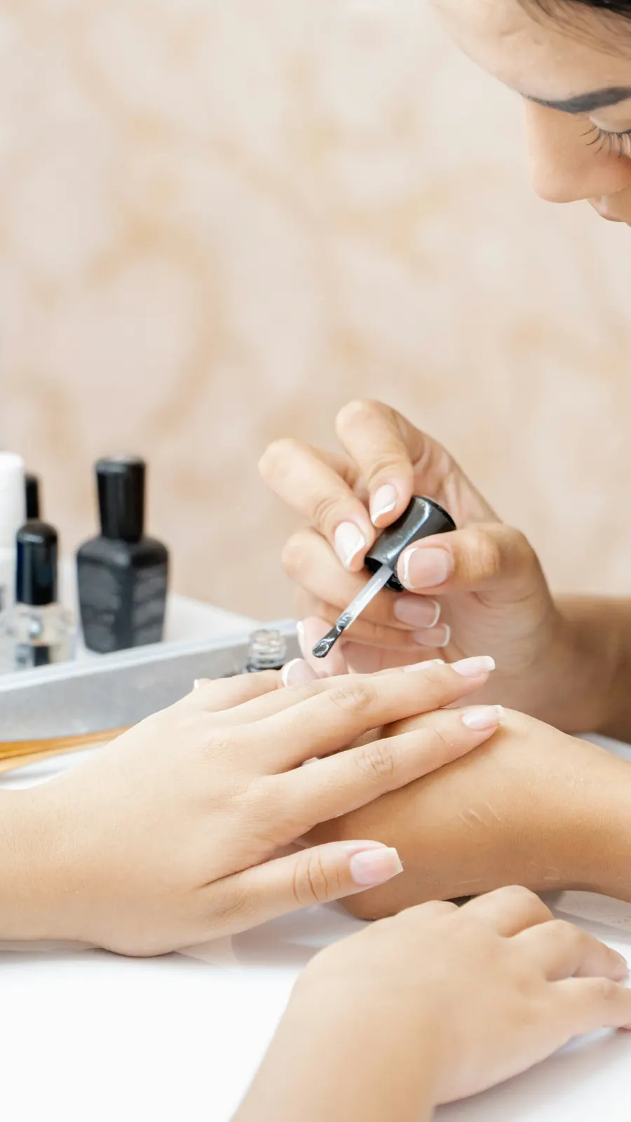 Mains d'une esthéticienne qui liment les ongles d'une cliente, gros plan, tons clairs