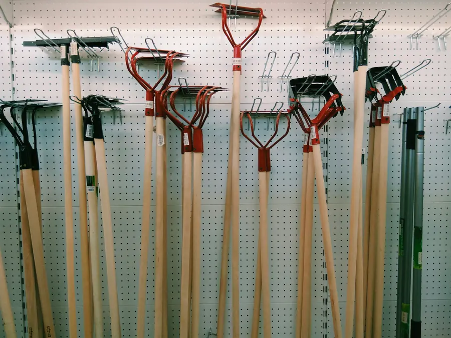 Mur d'outils de jardin (bêches, râteaux, sécateurs) en magasin