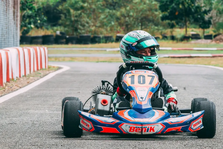 Jeune pilote de kart casqué, visière baissée, en pleine course