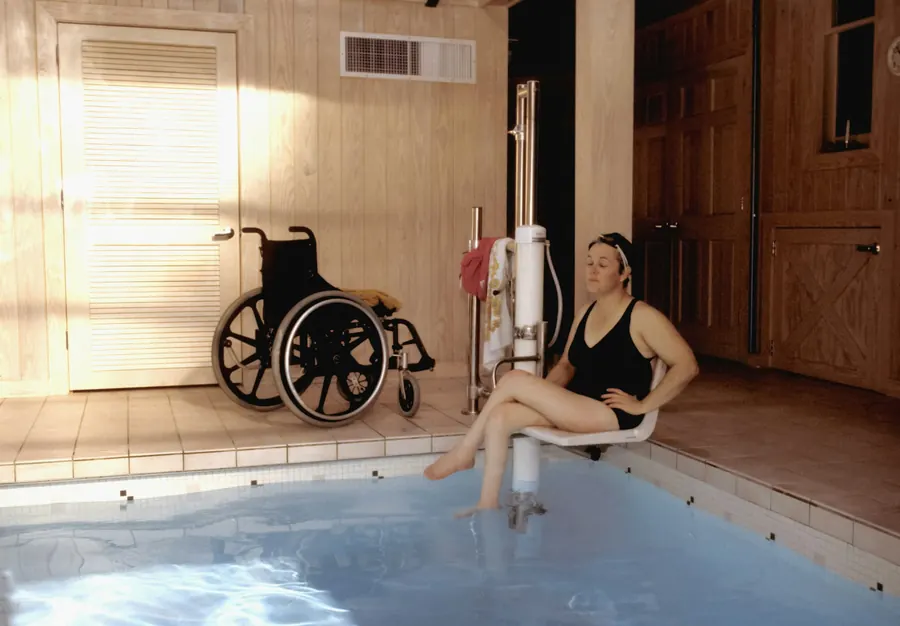 Femme en fauteuil roulant au bord d'un bassin de rééducation