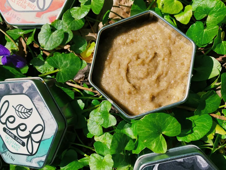 Pot de baume ouvert entouré de feuilles vertes, sans miel