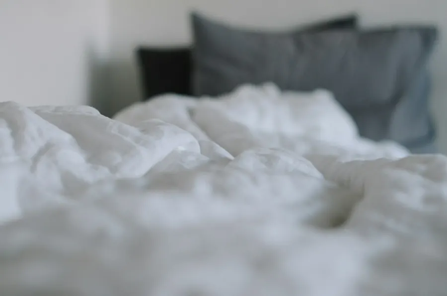 Lit avec draps blancs froissés, sans fenêtre de camping-car visible
