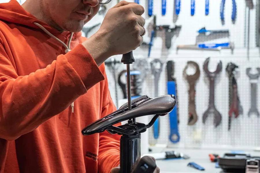 Mécanicien qui règle une selle de vélo, sans cliente visible