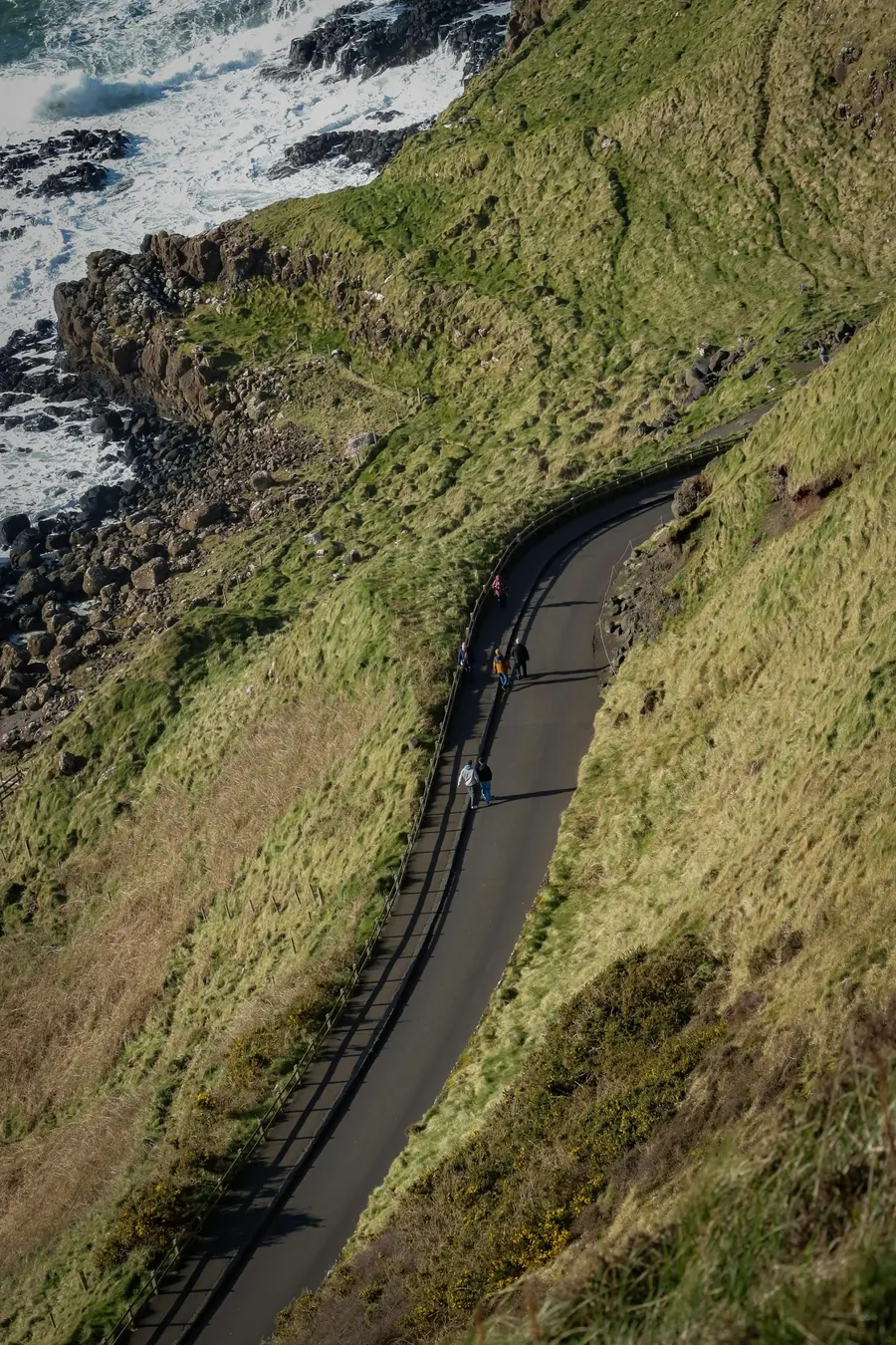 Sentier côtier sinueux vu du ciel, promeneurs au loin