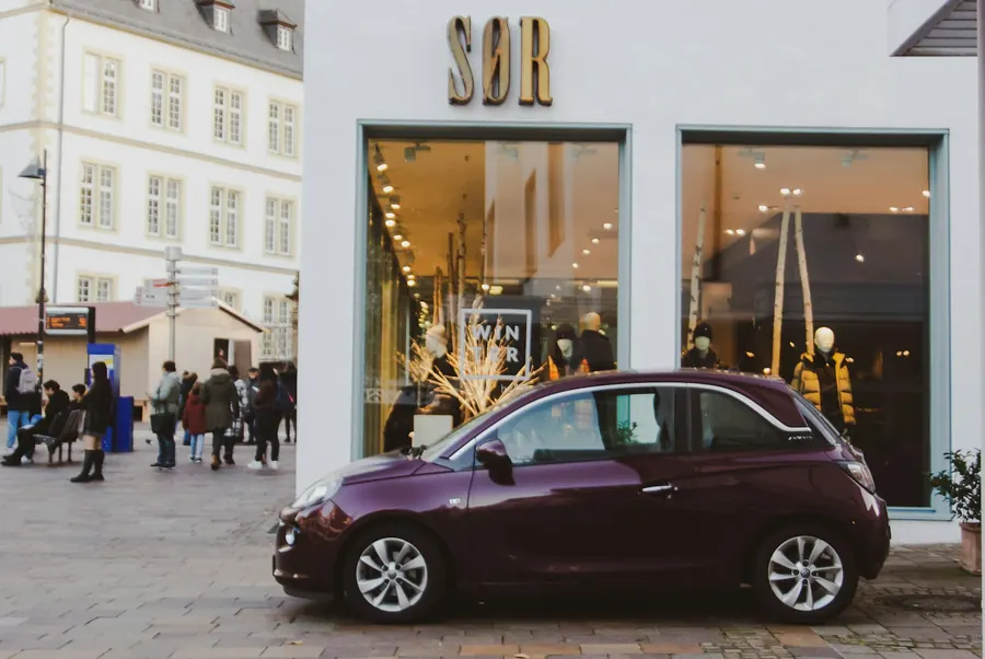 Rue commerçante avec une petite voiture garée, pas une agence de location