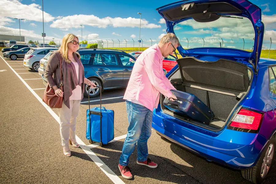 Famille qui charge des bagages dans le coffre d'un SUV, rue de ville
