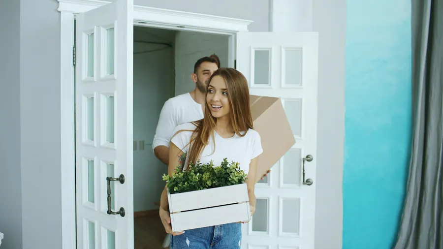 Couple qui porte des cartons devant un immeuble, sans fourgon visible