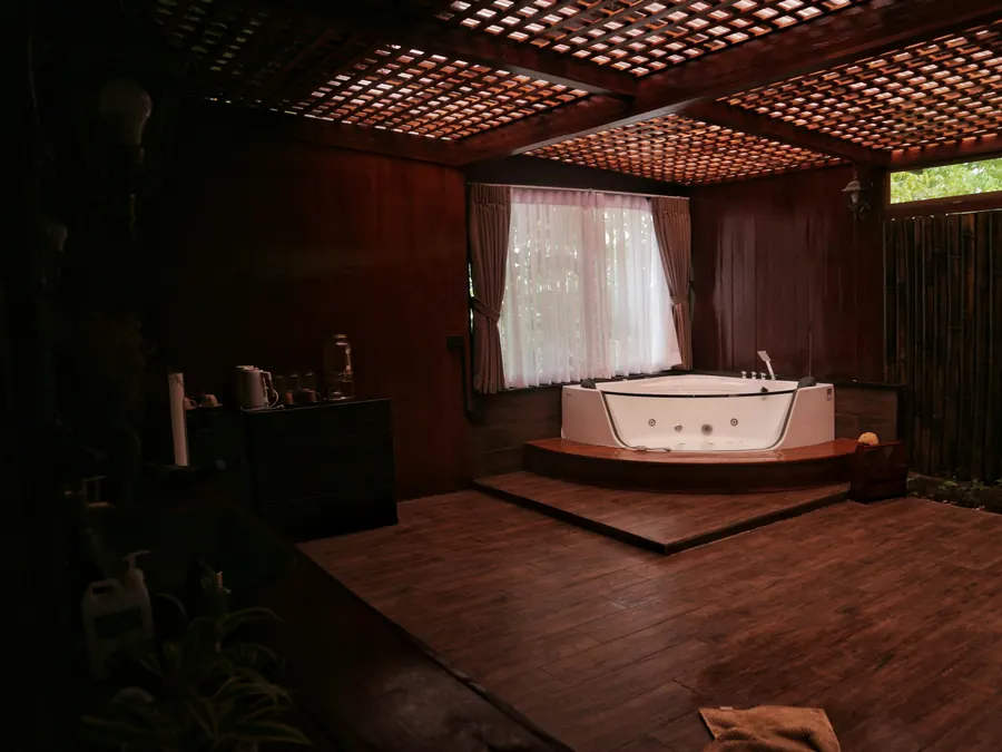 Baignoire balnéo d'angle dans une suite aux boiseries sombres, lumière tamisée