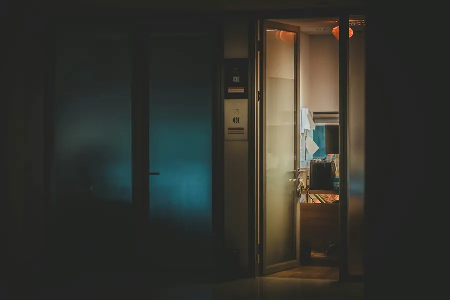 Chambre sombre avec porte vitrée, sauna non visible