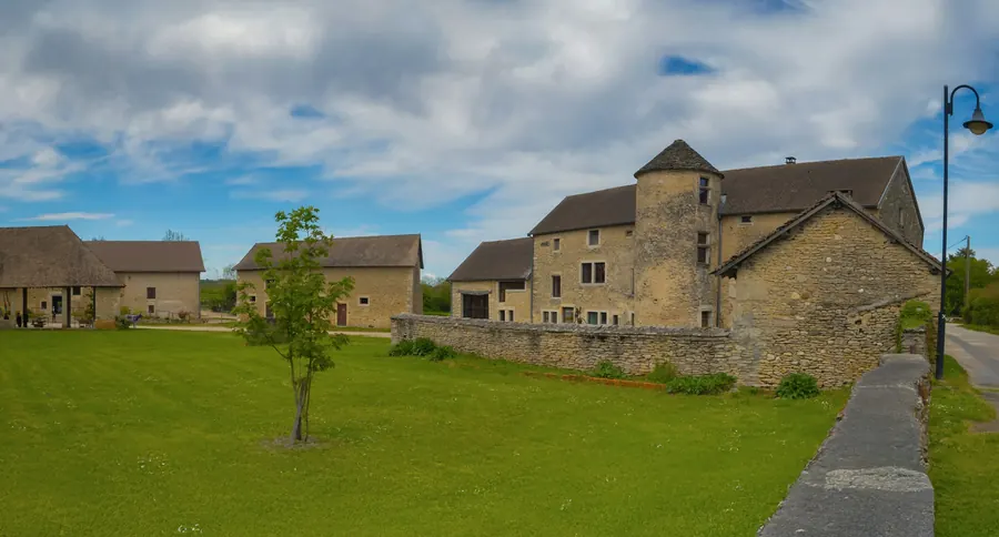 Bâtiment en pierre entouré d'une pelouse, sans enfants visibles