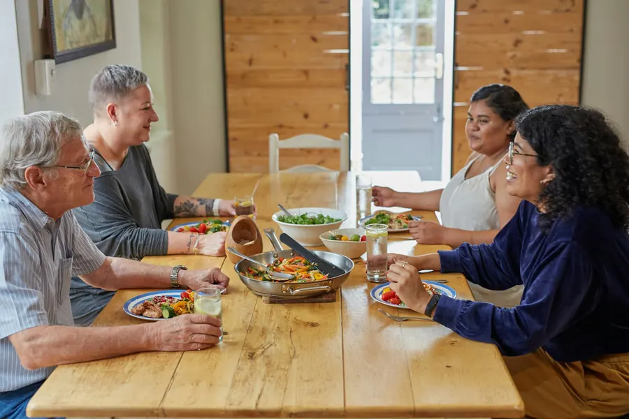 Repas convivial en famille autour d'une table en bois, à la maison