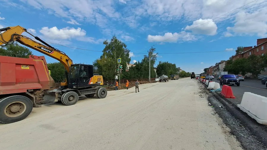 Pelleteuse et ouvrier sur une route en travaux, sans maisons en pierre visibles