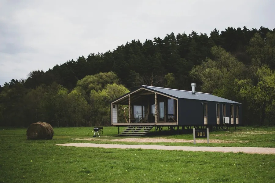 Maison en bois de plain-pied avec pelouse et arbres autour
