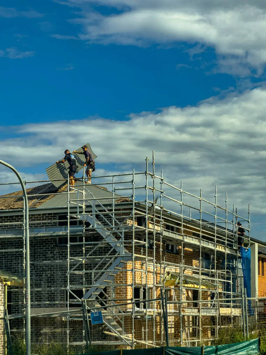 Ouvriers qui posent une toiture sur un chantier avec échafaudage