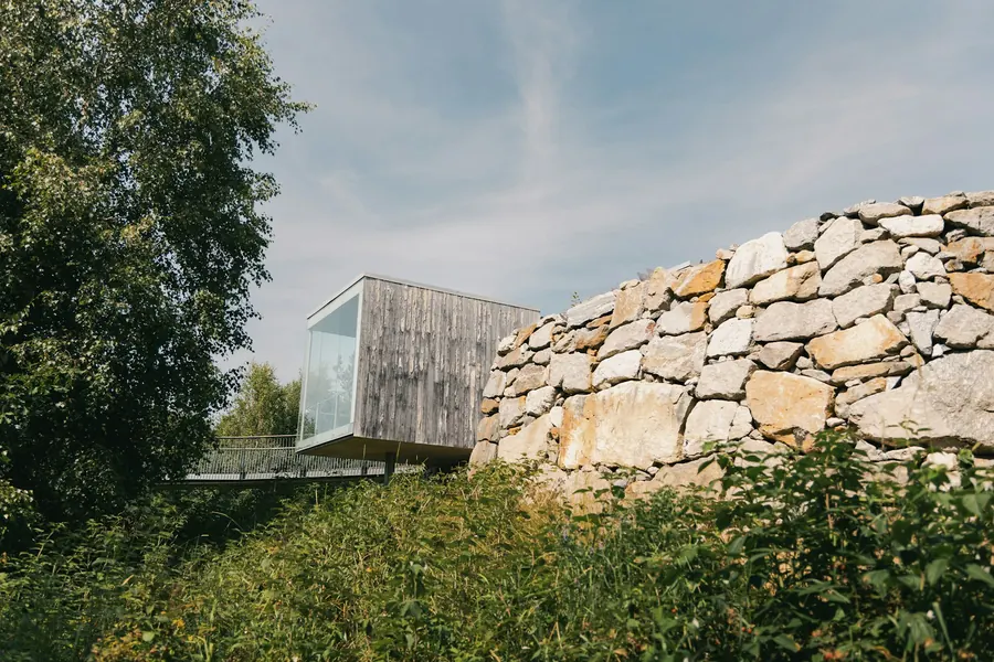 Bâtiment moderne en bois derrière un muret en pierre sèche