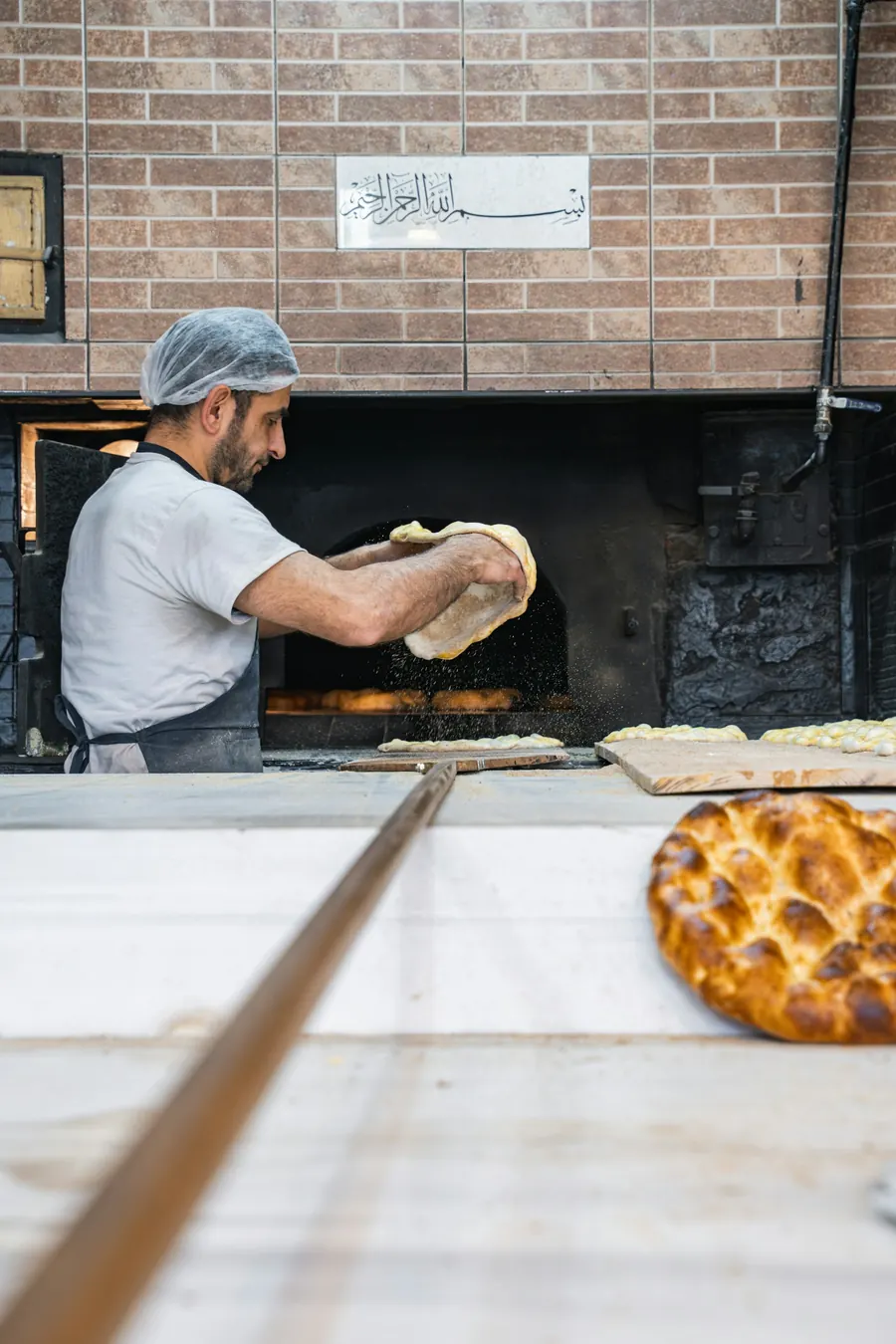 Boulanger qui enfourne des pains dans un four à soles, pelle en bois