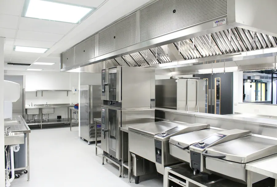 Cuisine professionnelle en inox, fours et plans de cuisson alignés, sans personne