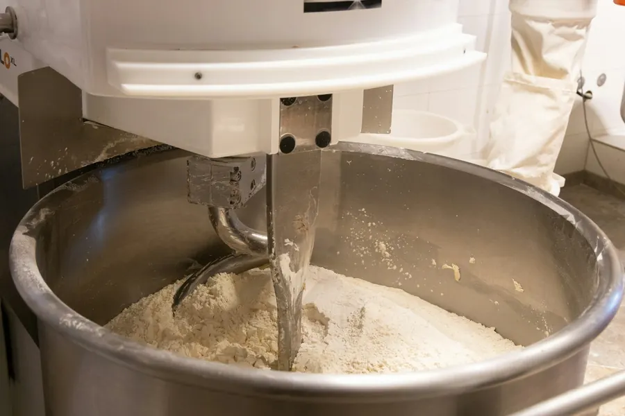 Pétrin à spirale rempli de pâte dans une cuisine professionnelle